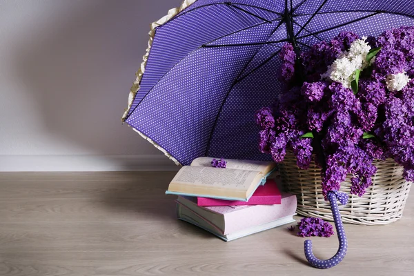 Beautiful lilac flowers with umbrella on floor in room close-up — Stock Photo, Image