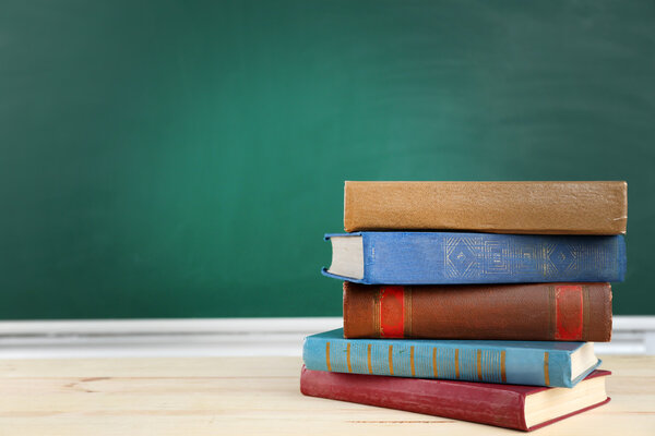Stack of books on desk, on blackboard background