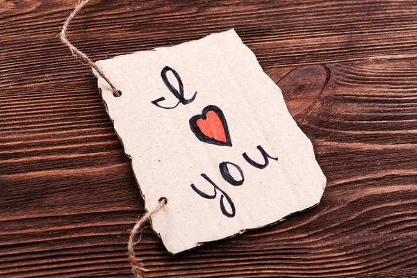 Napis kocham cię na kartonie wyłącznik na drewniane tła — Zdjęcie stockowe