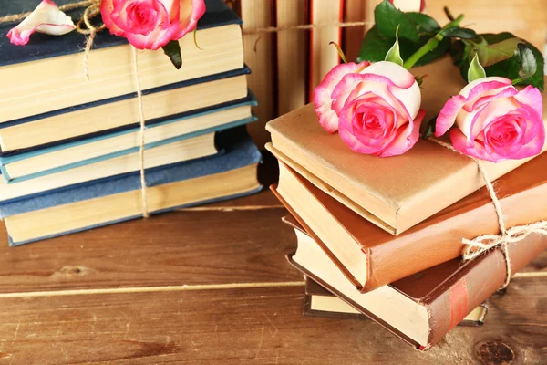 Tied books with pink roses on wooden background — Stock Photo, Image