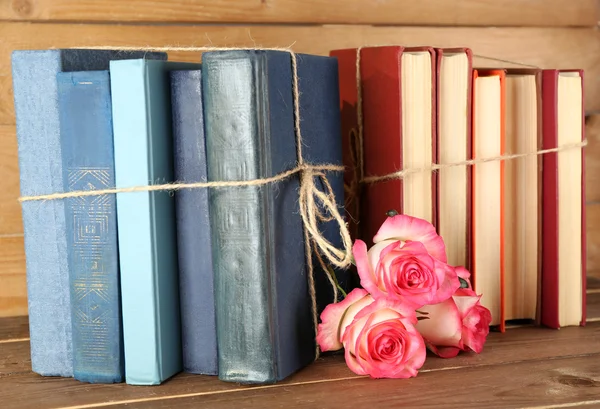 Tied books with pink roses on wooden background — Stock Photo, Image