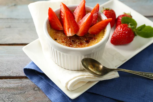 Crema brulee postre con fresas frescas en servilleta, sobre fondo de madera de color —  Fotos de Stock