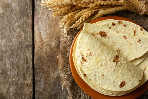 Pilha de tortilla de farinha de trigo integral caseira na placa, no fundo da mesa de madeira — Fotografia de Stock