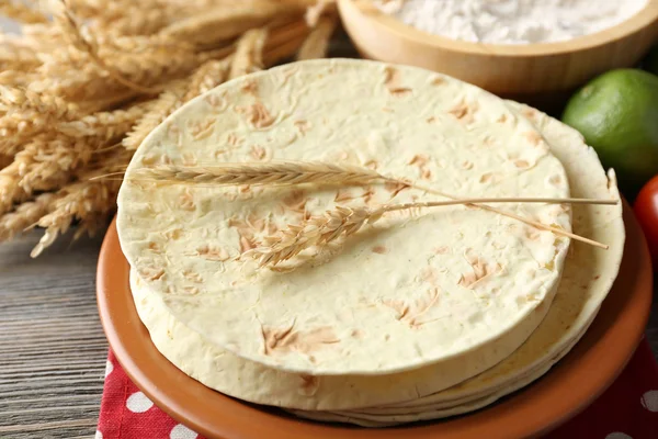Stos domowe pszennej mąki tortilli i warzyw na talerzu, na tle drewniany stół — Zdjęcie stockowe