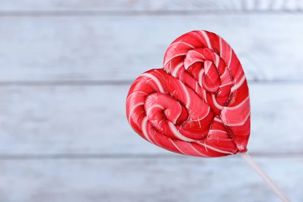 Bright lollipop in shape of heart on wooden background — Stock Photo, Image