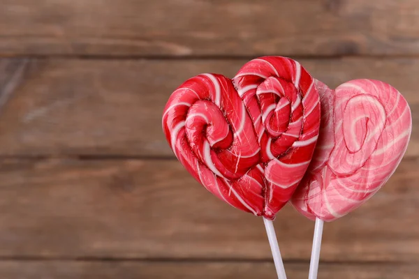 Bright lollipops in shape of heart on wooden background — Stock Photo, Image