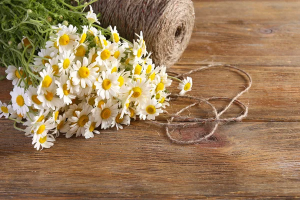 Beautiful bouquet of daisies with twine on wooden background — Stock Photo, Image