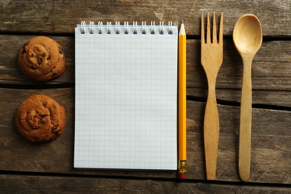 Open receptenboek en smakelijke bakkerij op houten achtergrond — Stockfoto