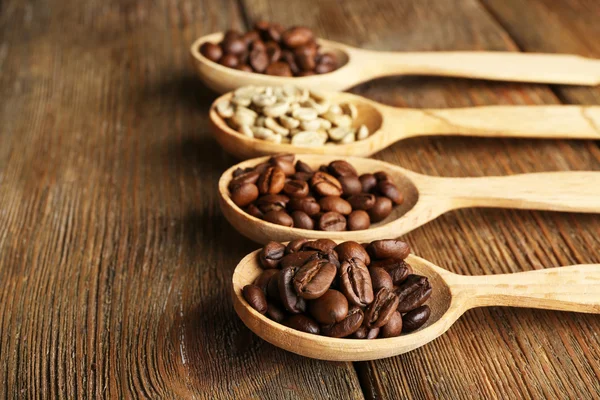 Kaffeebohnen in Löffeln auf Holzgrund — Stockfoto