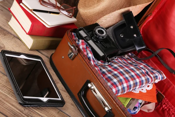 Packing suitcase for trip on wooden background — Stock Photo, Image