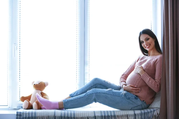 W ciąży kobieta siedziała na parapecie tło — Zdjęcie stockowe