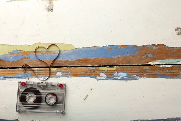 Cassette de audio con cinta magnética en forma de corazón sobre fondo de madera — Foto de Stock