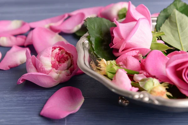 Mooie roze rozen in metalen plaat op houten tafel, close-up — Stockfoto