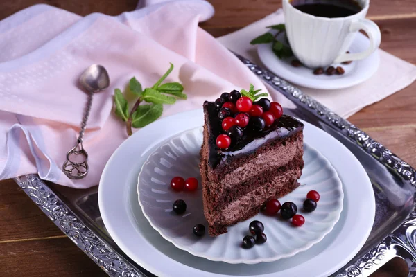 Delicioso pastel de chocolate con bayas y taza de café en la mesa de cerca —  Fotos de Stock