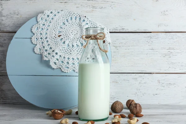 Milk in glassware and walnuts on wooden background — Stock Photo, Image