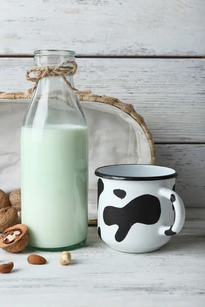 Milk in glassware and walnuts on wooden background — Stock Photo, Image