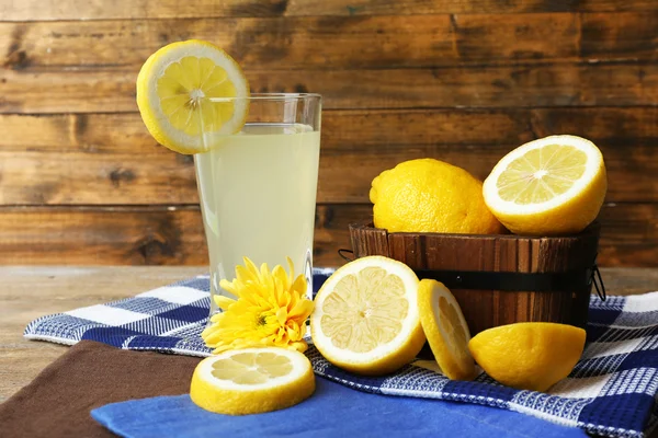 Natura morta con succo di limone e limoni affettati su fondo di legno — Foto Stock