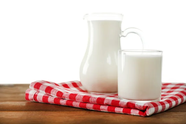 Brocca e bicchiere di latte su tavolo di legno, su sfondo bianco — Foto Stock