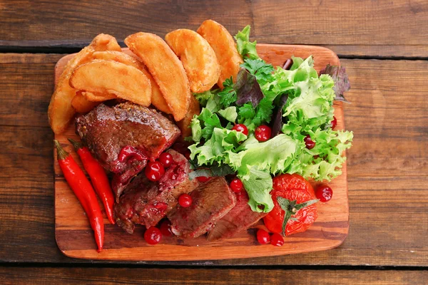 牛肉调味蔓越莓酱，烤的土豆切片在砧板上木制的背景上 — 图库照片