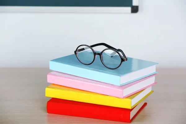 Hoop boeken en bril op tabel in de klas — Stockfoto