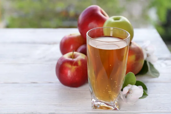 Bicchiere di succo di mela e mele su tavolo di legno — Foto Stock
