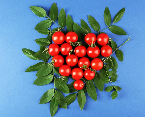 Черри помидоры расположены в форме сердца с зелеными листьями — стоковое фото