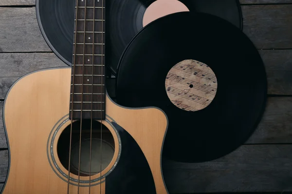 Guitar and vinyl records on wooden table — Stock Photo, Image