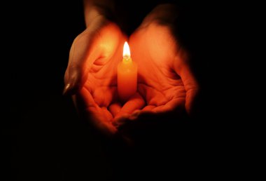 Siyah arka planda kadın ellerinde mum.