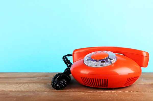 Telefono retrò su tavolo di legno su sfondo blu — Foto Stock