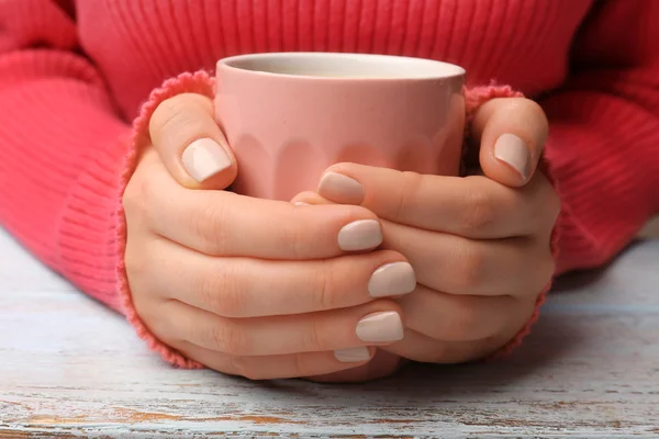 Mãos femininas segurando xícara de café na mesa de madeira perto — Fotografia de Stock