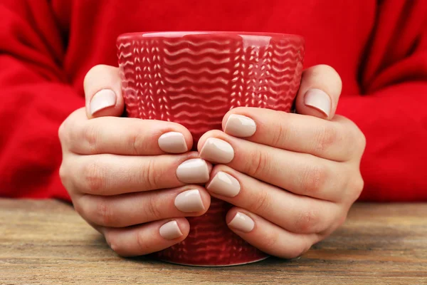 Frauenhände halten Tasse Kaffee auf Holztisch in Großaufnahme — Stockfoto