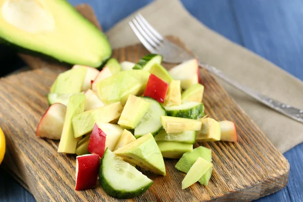 Sliced avocado and apple on cutting board close up — Stock Photo, Image