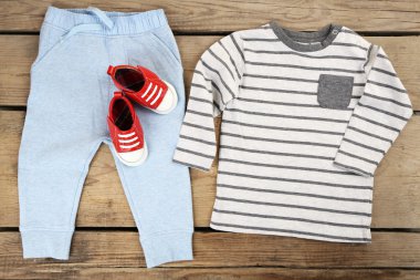 Clothes for baby boy on wooden background clipart