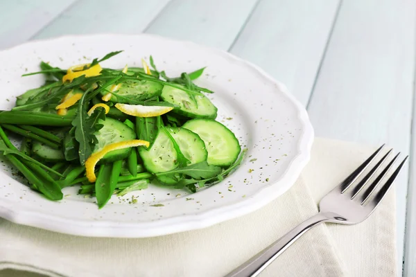 Salada verde com pepino, rúcula e casca de limão em fundo de madeira — Fotografia de Stock