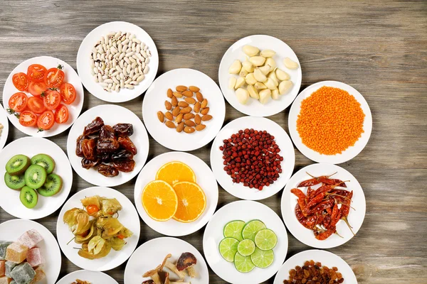 Different products on saucers on wooden table, top view — Stock Photo, Image