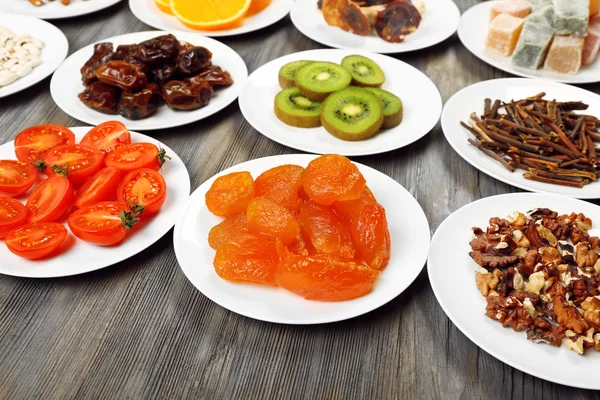 Different products on saucers on wooden table, closeup — Stock Photo, Image