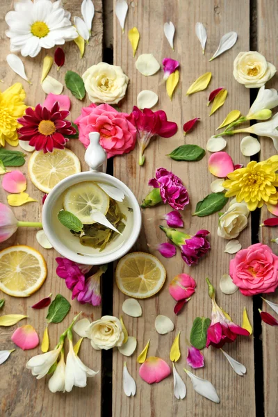 Cup of herbal tea with beautiful flowers, on wooden background — Stock Photo, Image