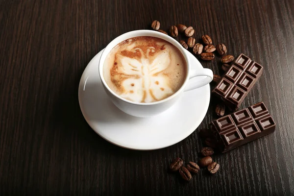 与谷物和木制背景上的巧克力咖啡拿铁艺术 cup — 图库照片