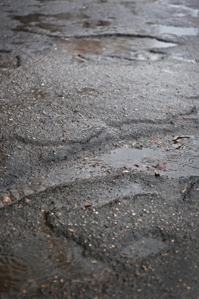 Holes with puddles on damaged asphalt background — Stock Photo, Image