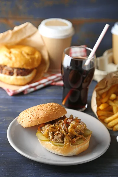 Gustosi hamburger e patatine fritte su piatto, su fondo tavolo in legno. Concetto di cibo malsano — Foto Stock