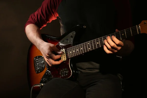 Jovem tocando guitarra elétrica no fundo escuro — Fotografia de Stock