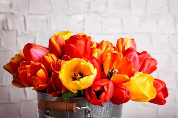 Mooi boeket van tulpen in metalen emmer op muur achtergrond — Stockfoto