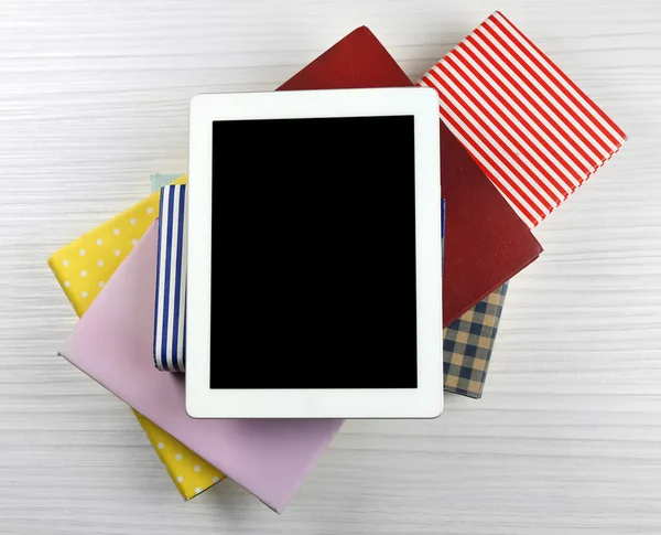 Notebook on top of pile of books and magazines on wooden background — Stock Photo, Image