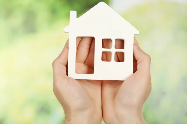 Vrouwelijke handen met huis op groene onscherpe achtergrond — Stockfoto