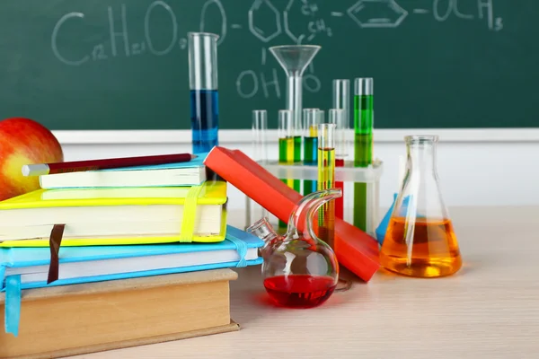 Desk in chemistry class with test tubes on green blackboard background — Stock Photo, Image