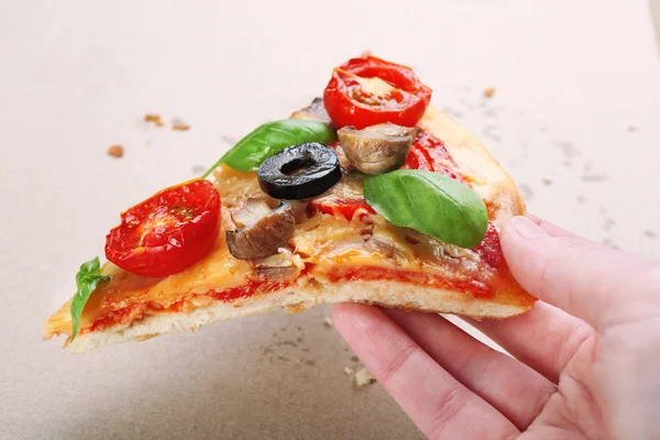 Hand bedrijf plak van smakelijke pizza met groenten en basilicum close-up — Stockfoto