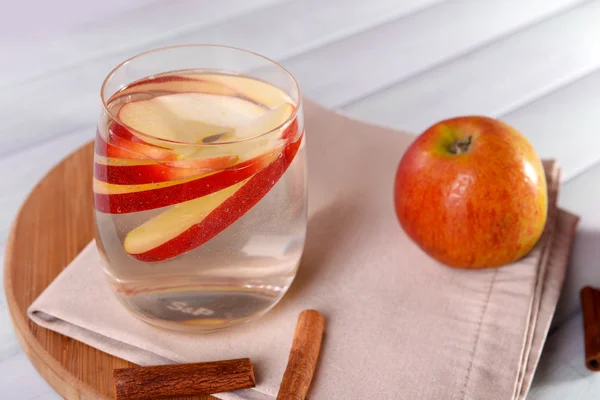 Glass of apple cider with fruits and cinnamon on table close up — Stock Photo, Image