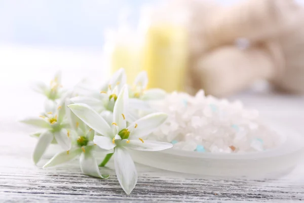 Sal marinho, flores e tratamento de spa na tabela de madeira da cor, no fundo claro — Fotografia de Stock