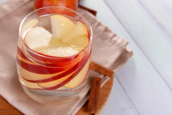 Glass of apple cider with fruits and cinnamon on table close up — Stock Photo, Image