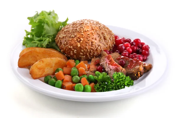 Wołowina z sosem żurawinowym, ziemniaki pieczone plasterki, warzywa i kok na talerzu, na białym tle — Zdjęcie stockowe